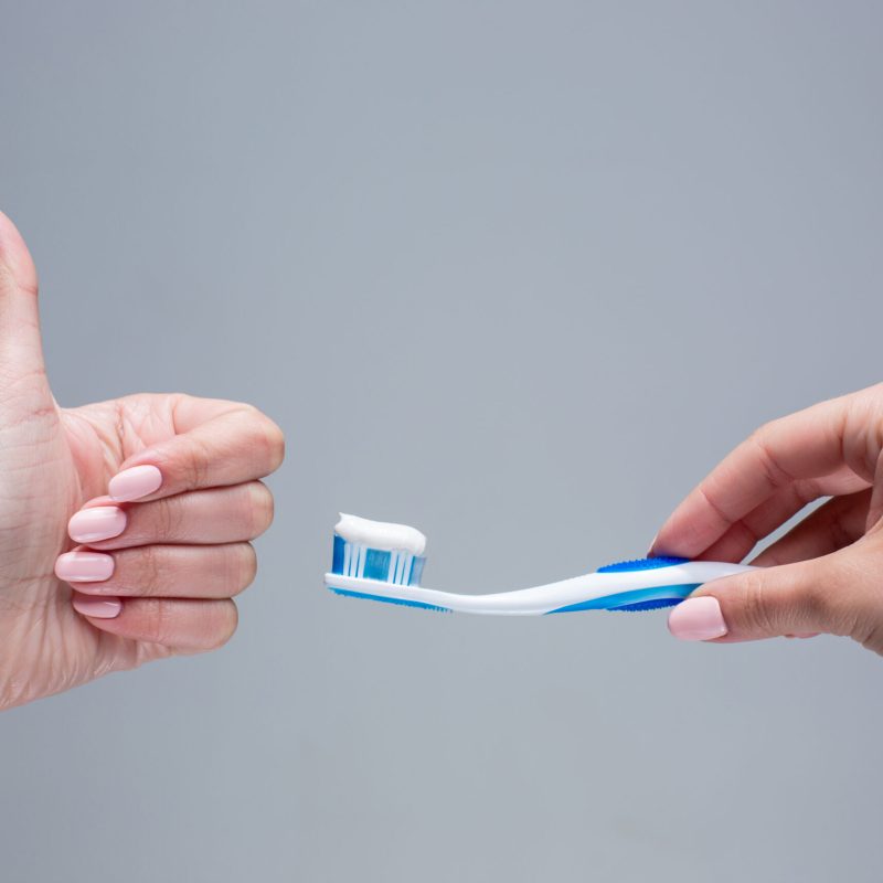 Toothbrush in woman's hands on gray background